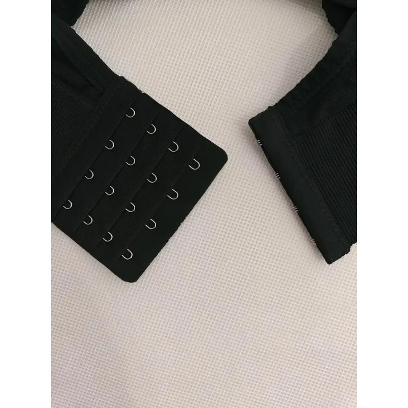 Black strapless bra with metal hooks on a textured white surface