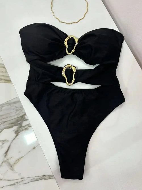 Black swimsuit with gold hardware on a marble surface