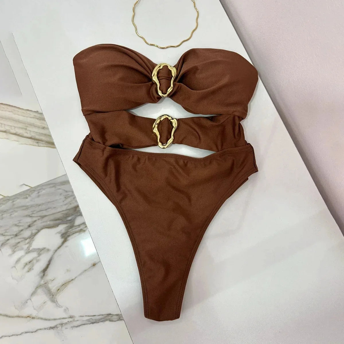 Brown bikini with gold rings on a white surface