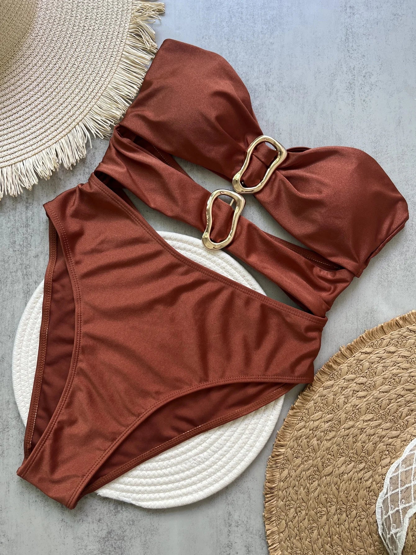 Brown bikini set with gold hardware on a textured surface