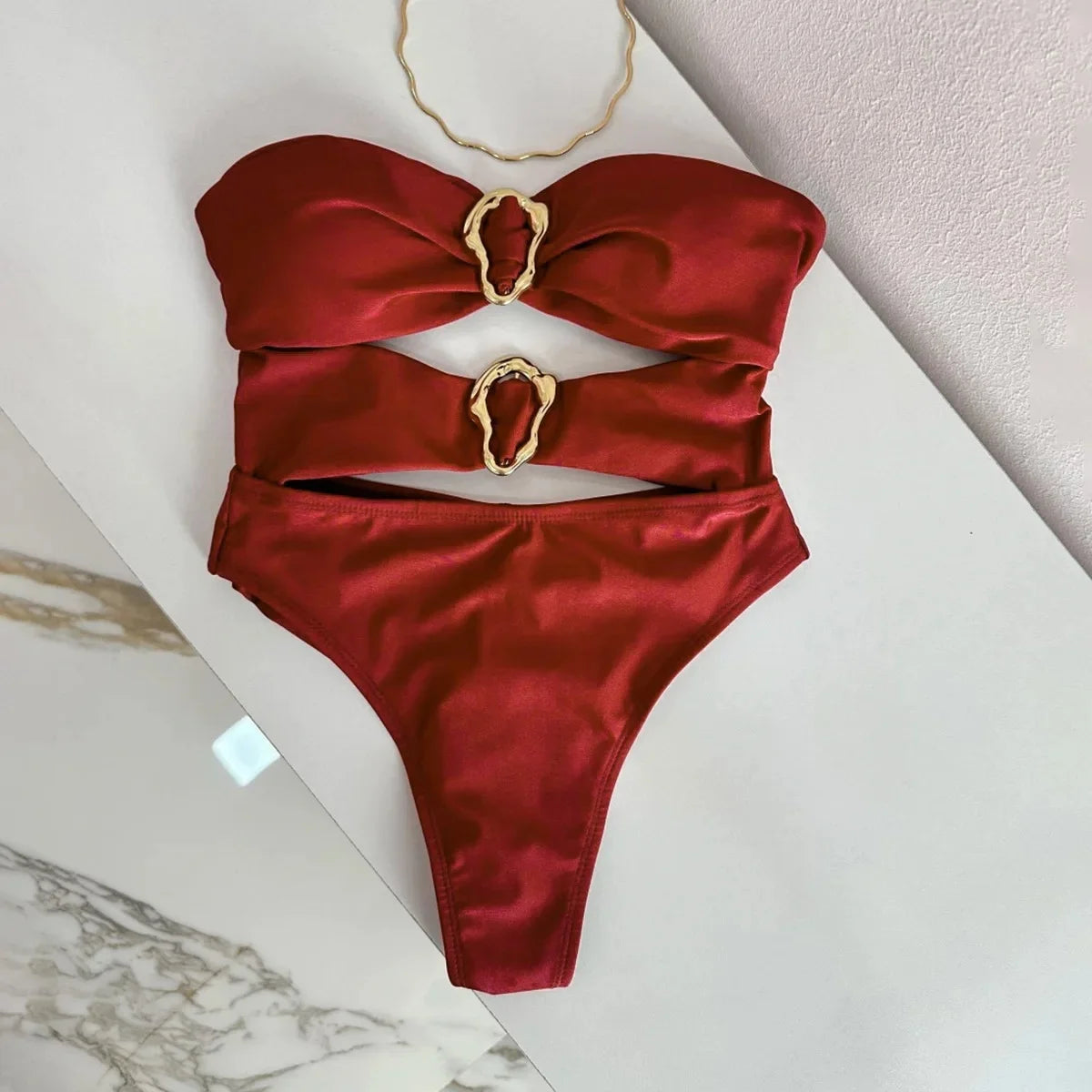 Red bikini with gold accents on a marble surface