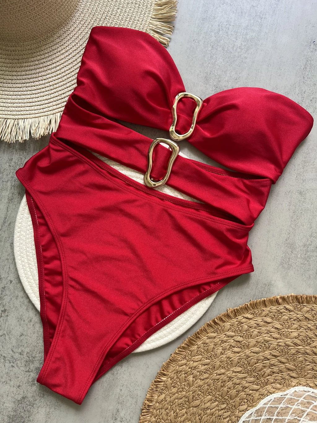 Red swimsuit with gold buckle on a textured surface