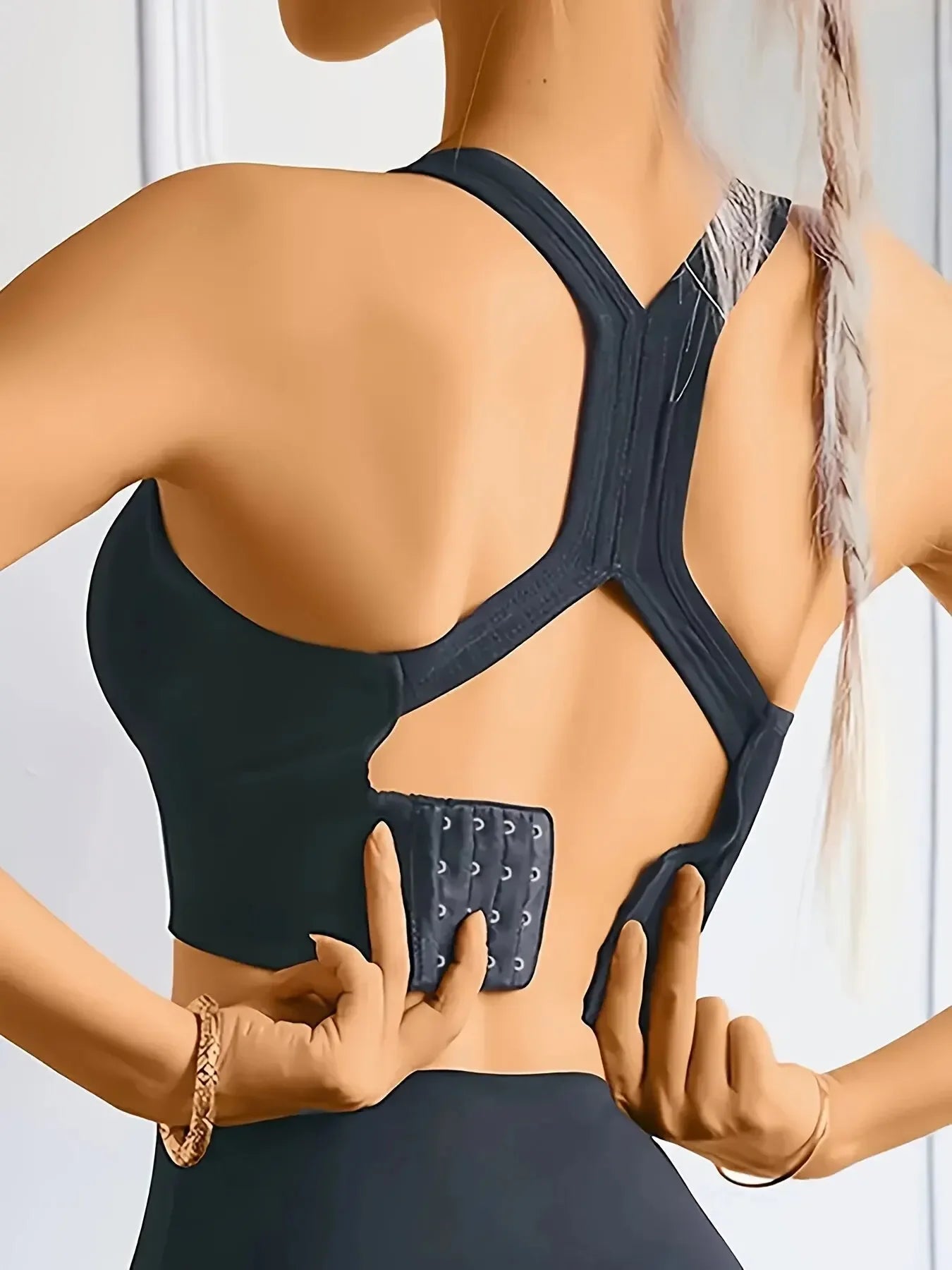 Person wearing a black sports bra with a back support device.